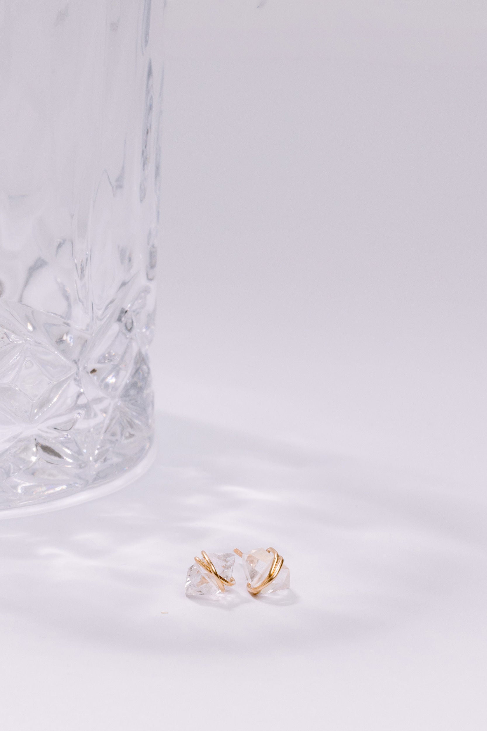 Clear glass earring with gold accent on a white marble surface