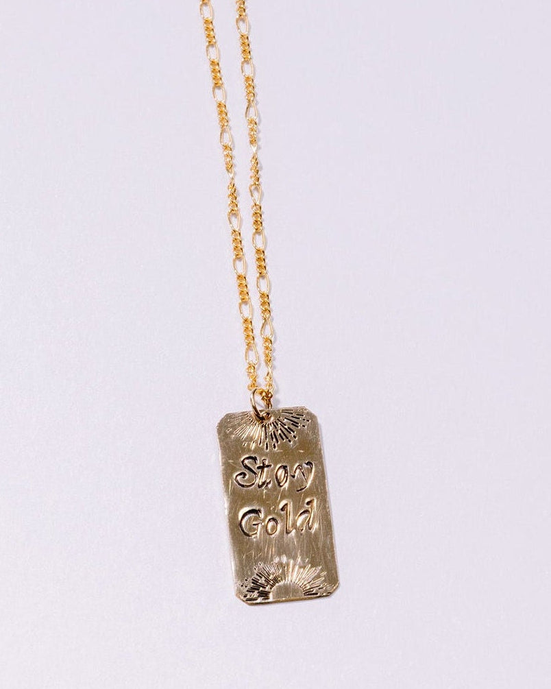 Gold necklace with a pendant on a light gray background
