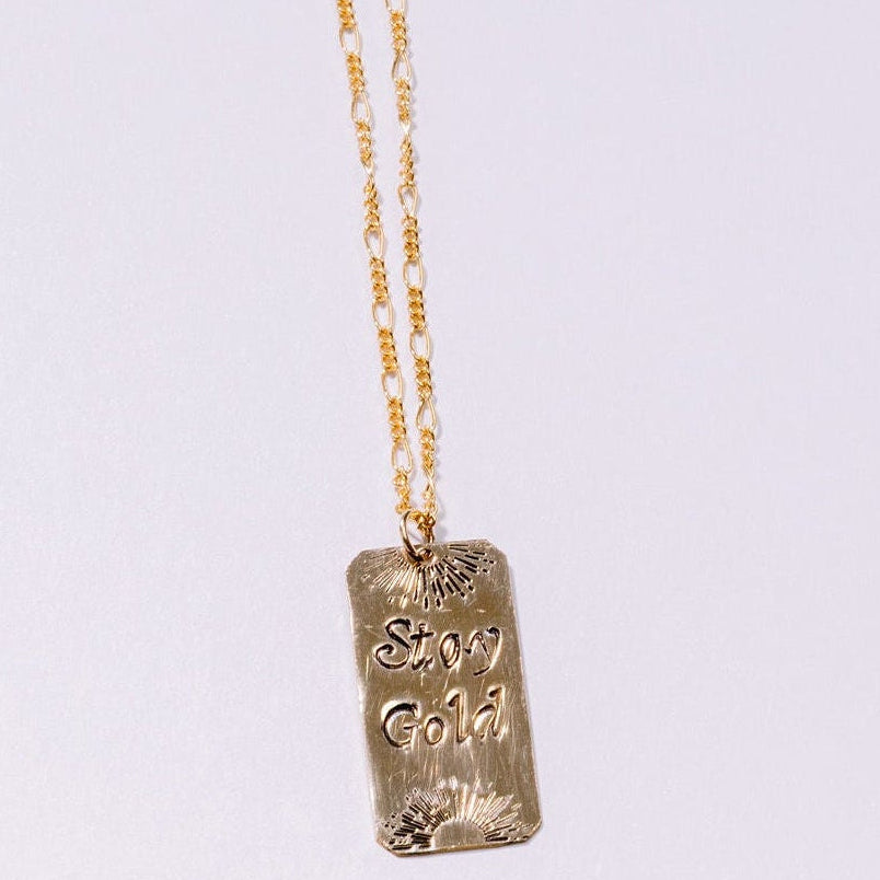 Gold necklace with a pendant on a light gray background