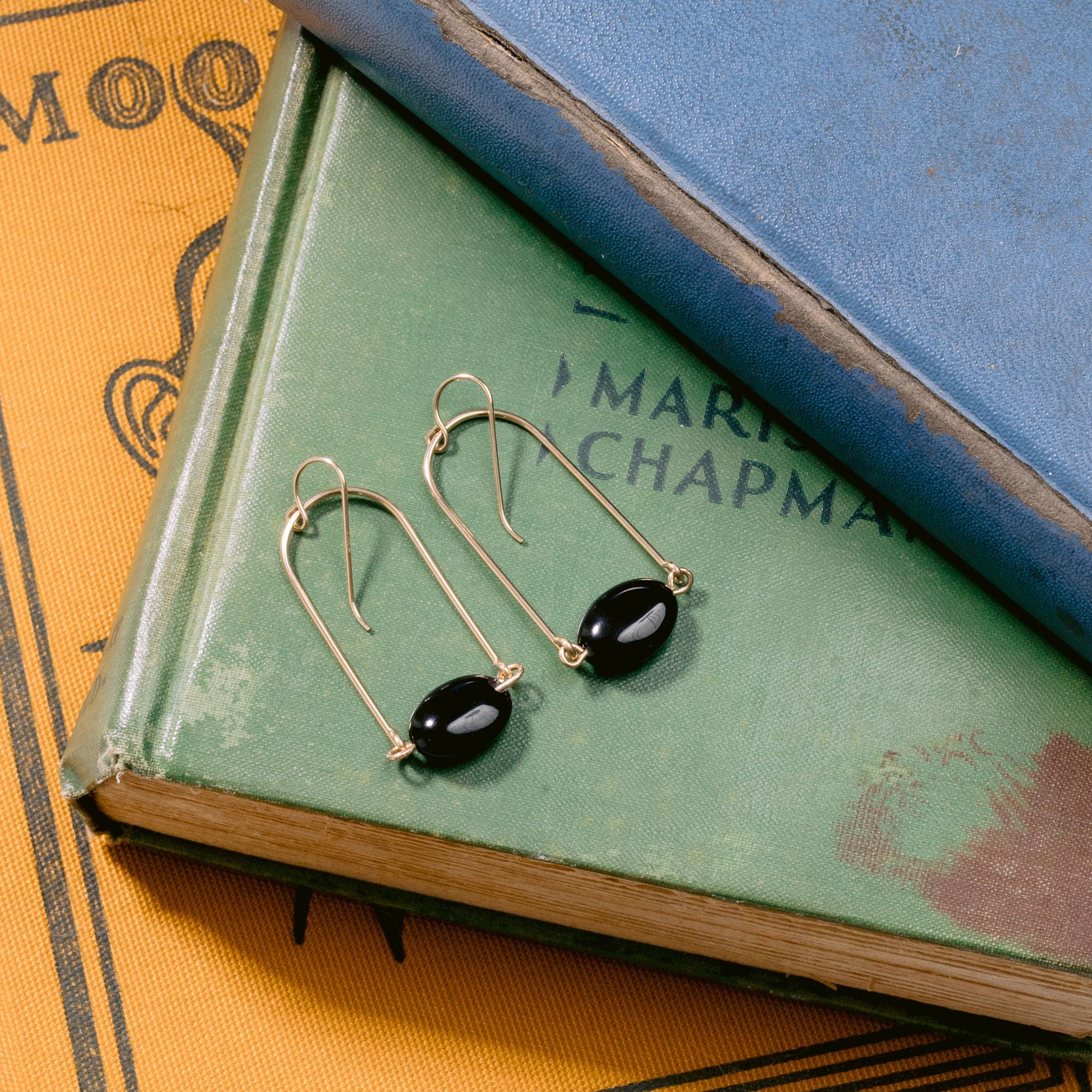 Pair of gold earrings with black stones on a stack of books