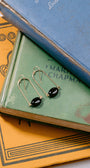 Pair of gold earrings with black stones on a stack of books