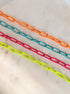 Neon enamel chains laying on a marble background