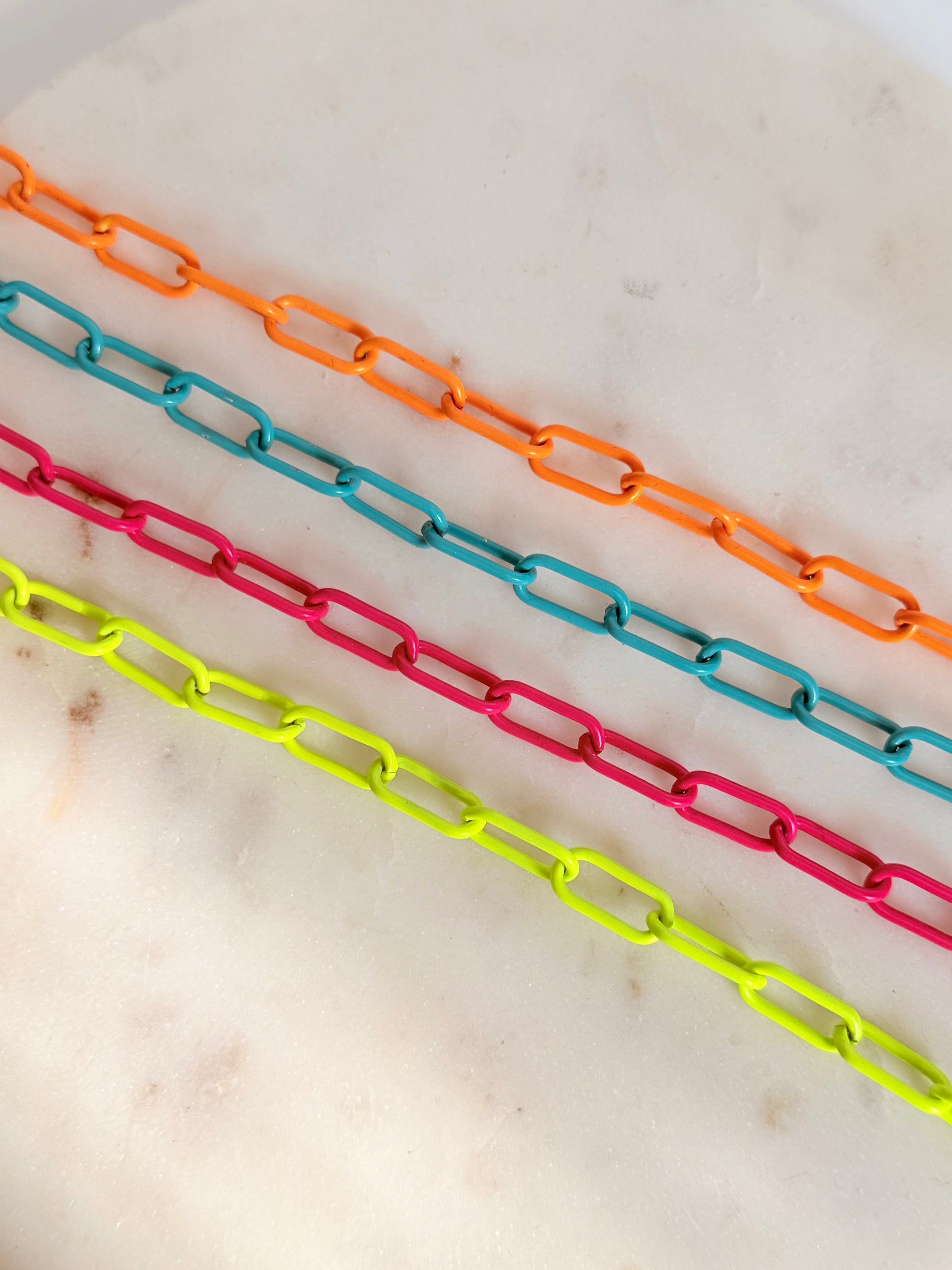 Neon enamel chains laying on a marble background