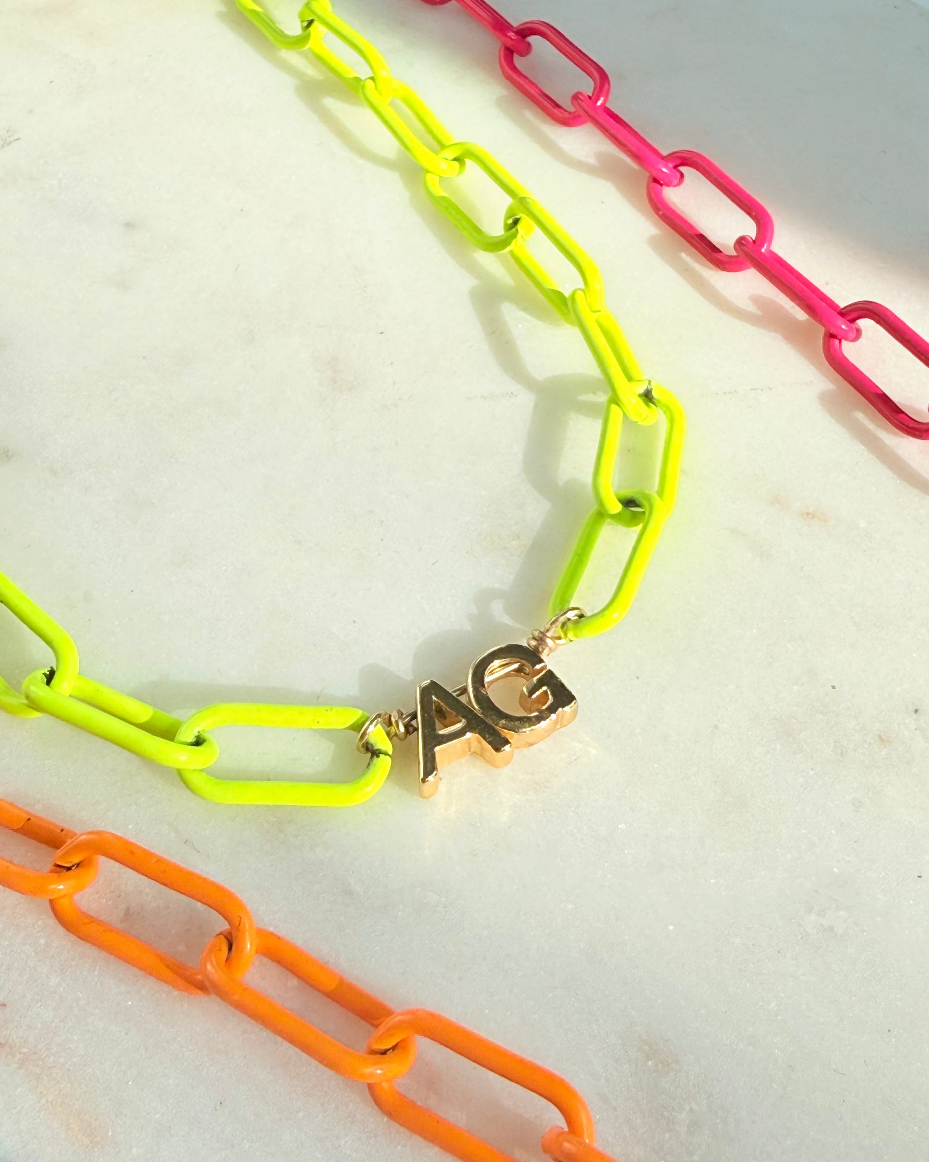 Neon enamel necklace close up with 2 gold initials 