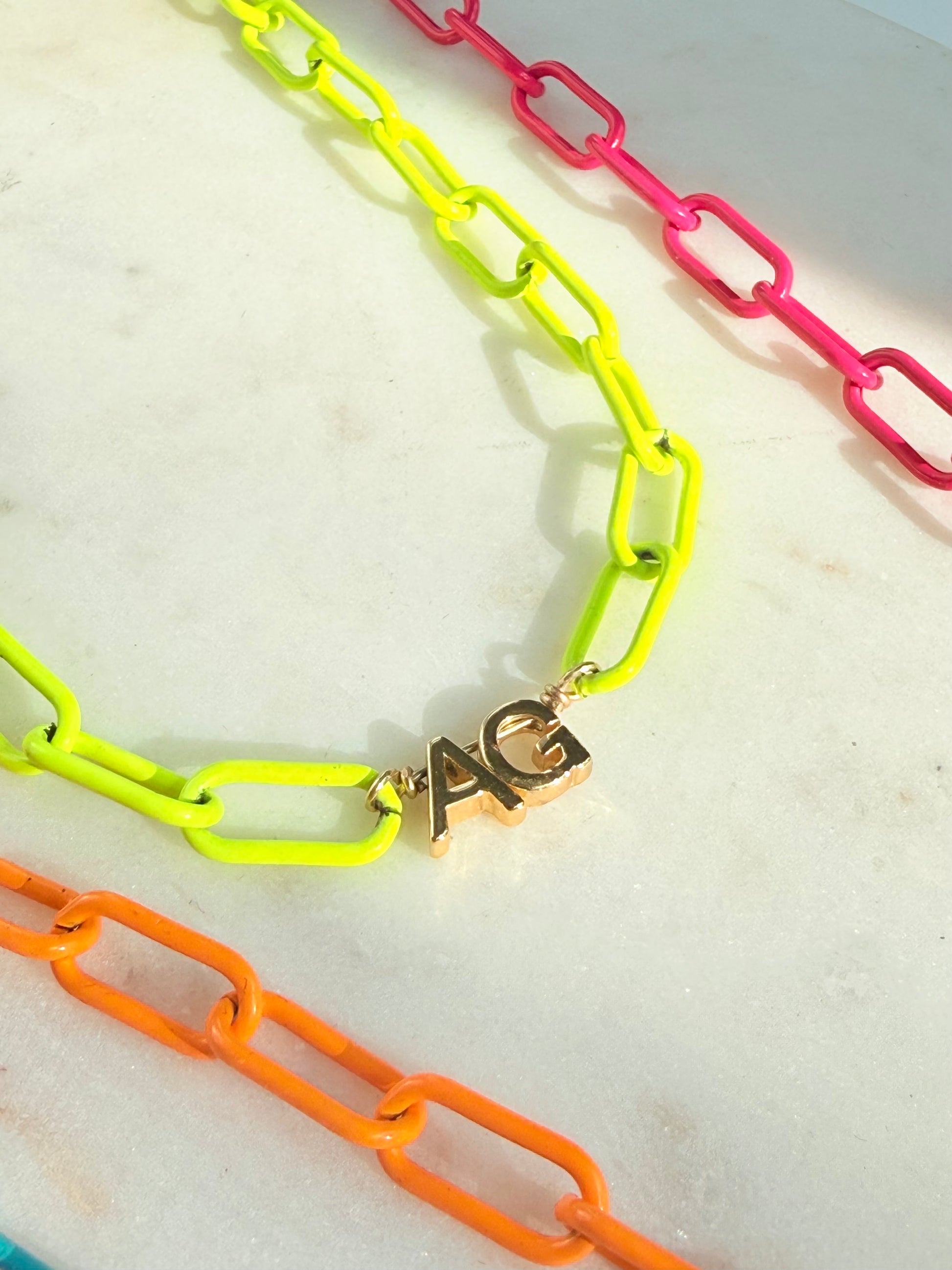 Neon enamel necklace close up with 2 gold initials 