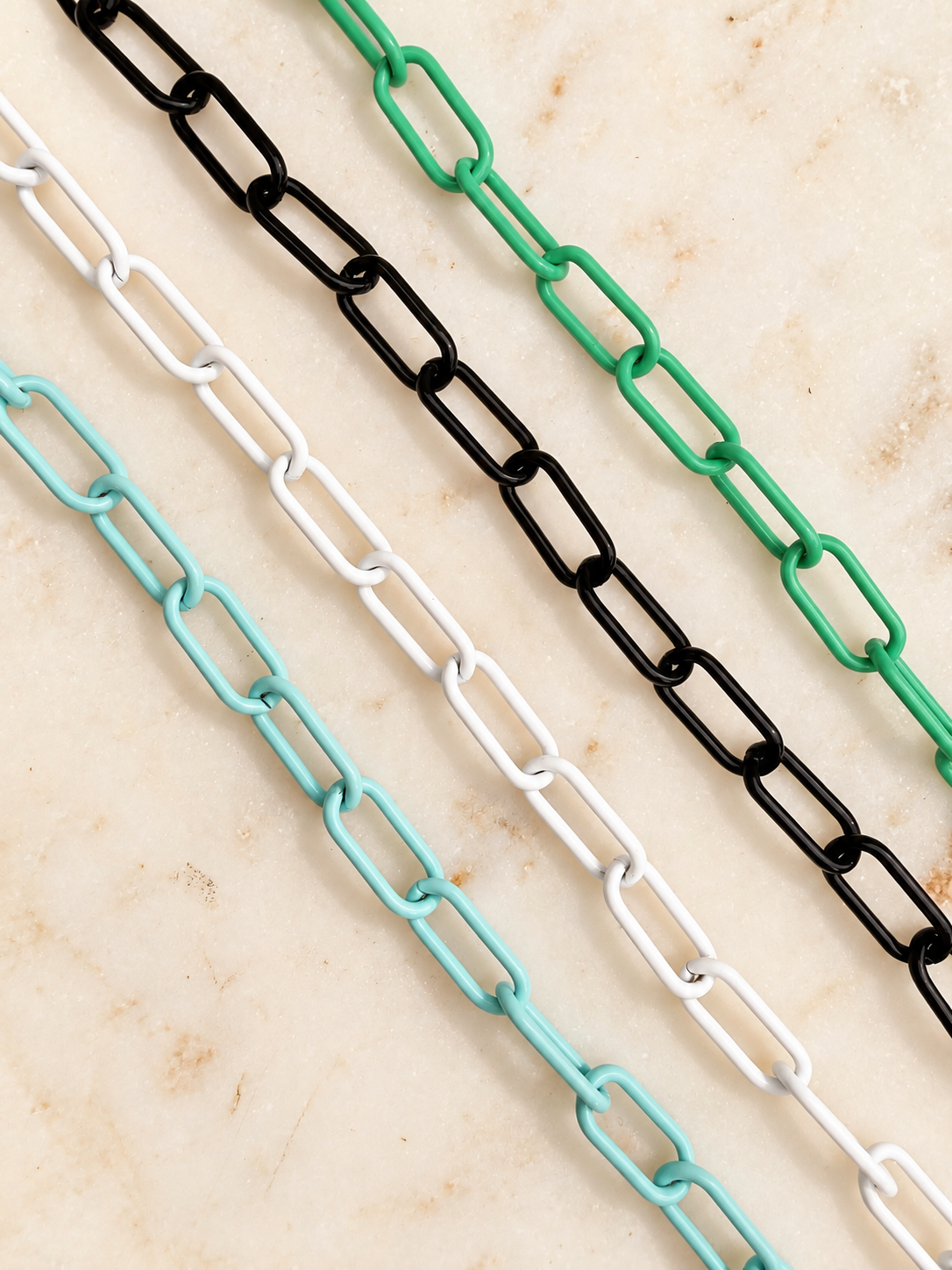 4 paperclip chains in mint, white, black and green on an ivory marble background