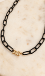 Black paperclip chain with 2 gold initials on a ivory marble background