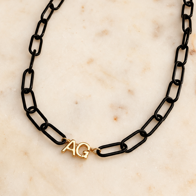 Black paperclip chain with 2 gold initials on a ivory marble background