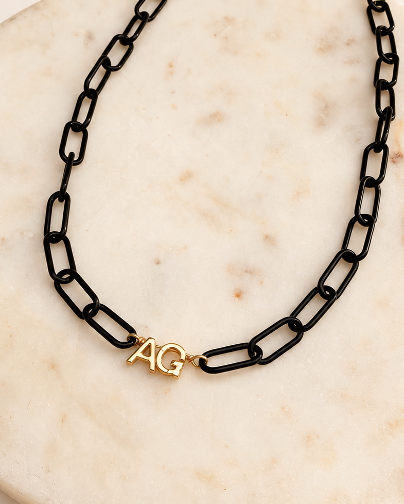 Black paperclip chain with 2 gold initials on a ivory marble background