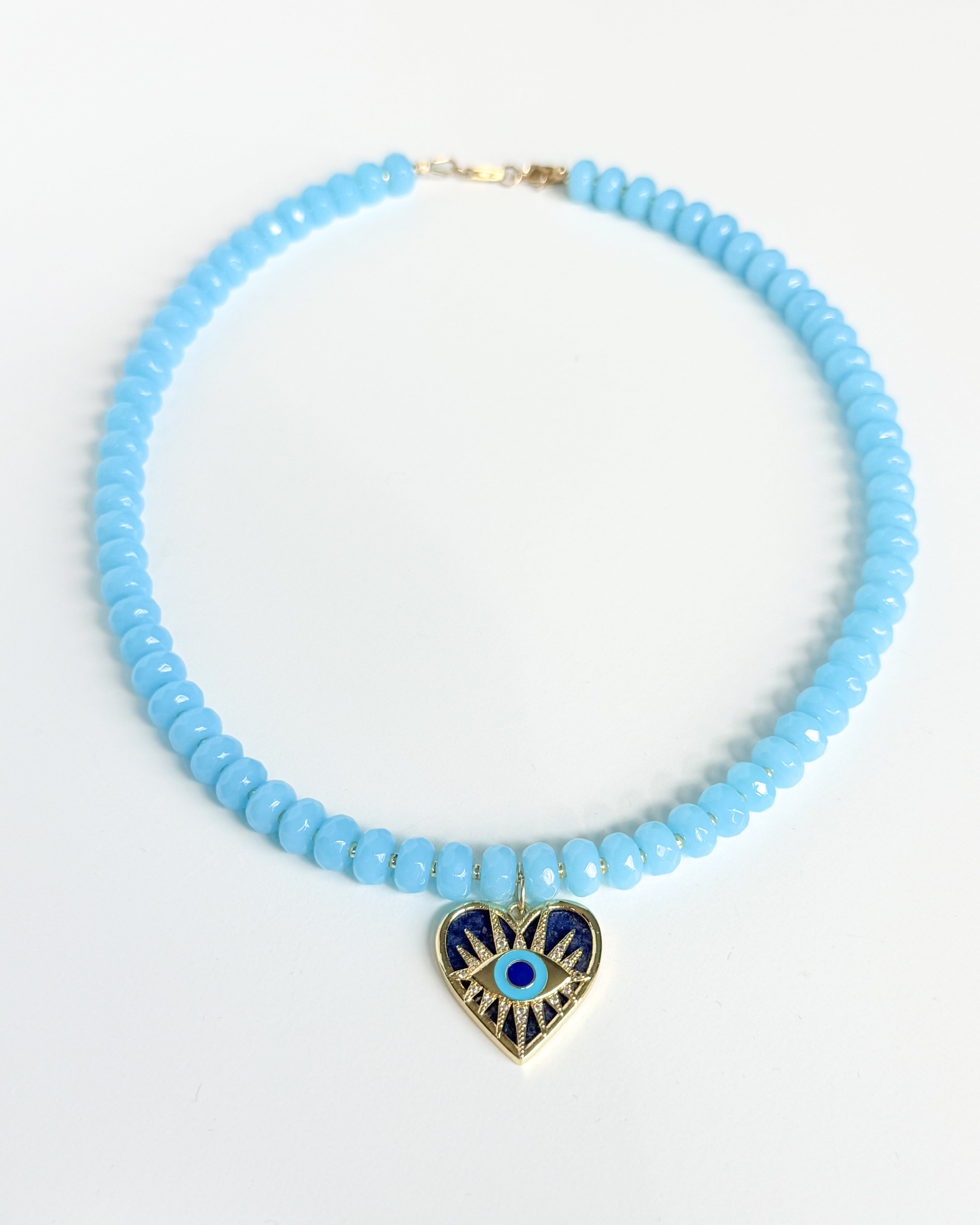 Necklace with light blue beads and a heart-shaped pendant on a white background