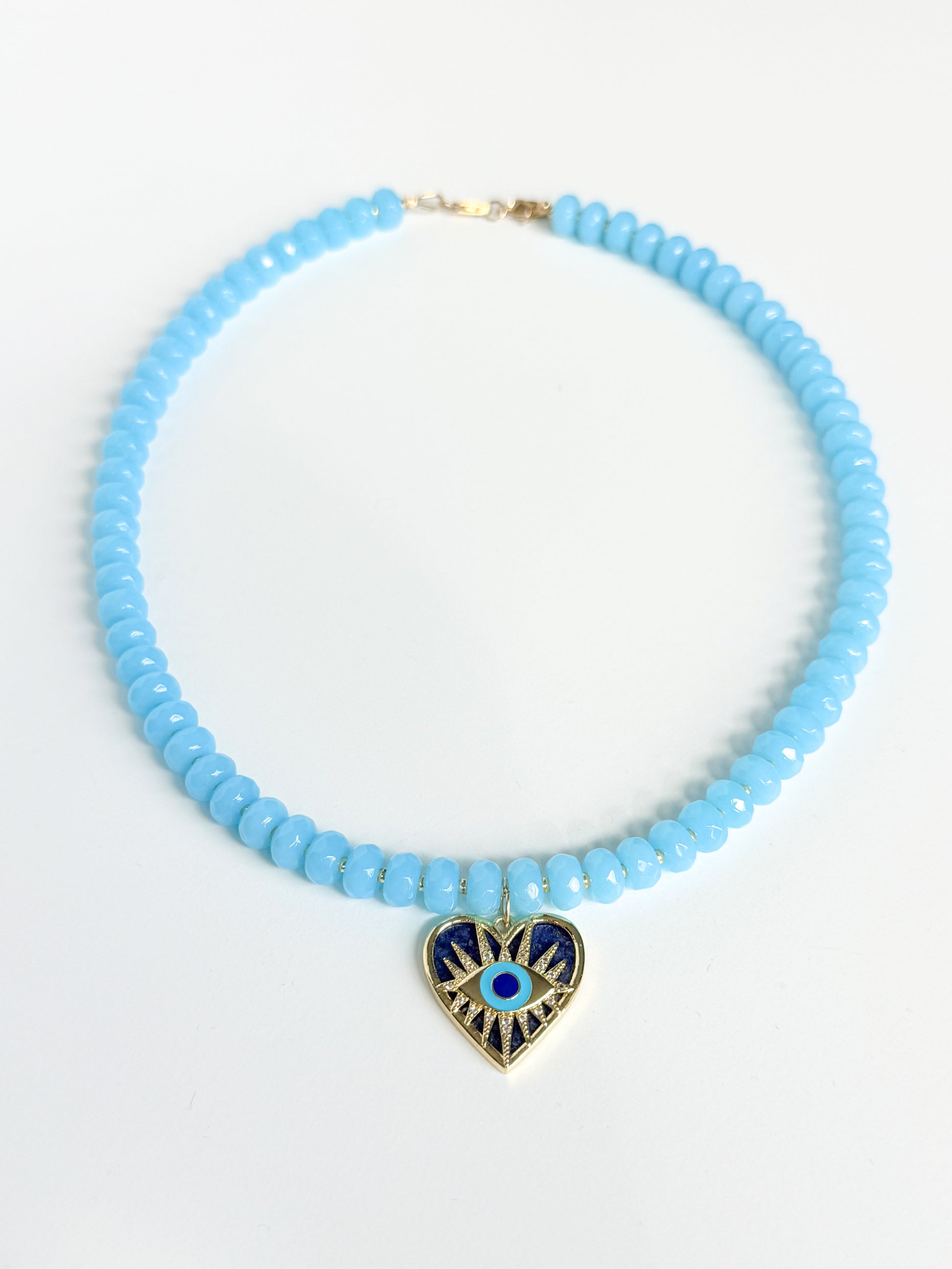 Necklace with light blue beads and a heart-shaped pendant on a white background