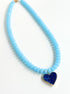 Necklace with light blue beads and a blue heart pendant on a white background