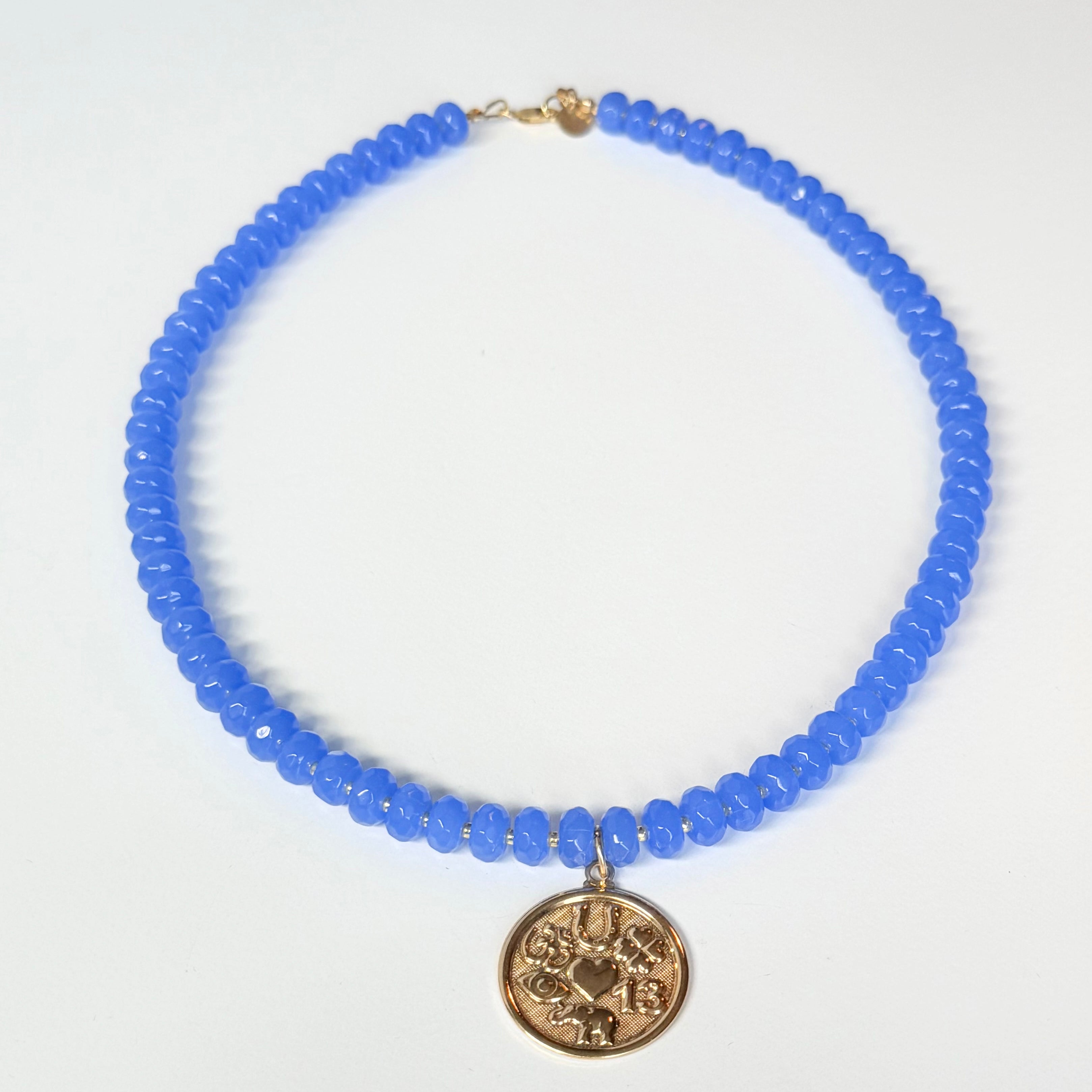 Blue beaded necklace with a gold pendant on a white background