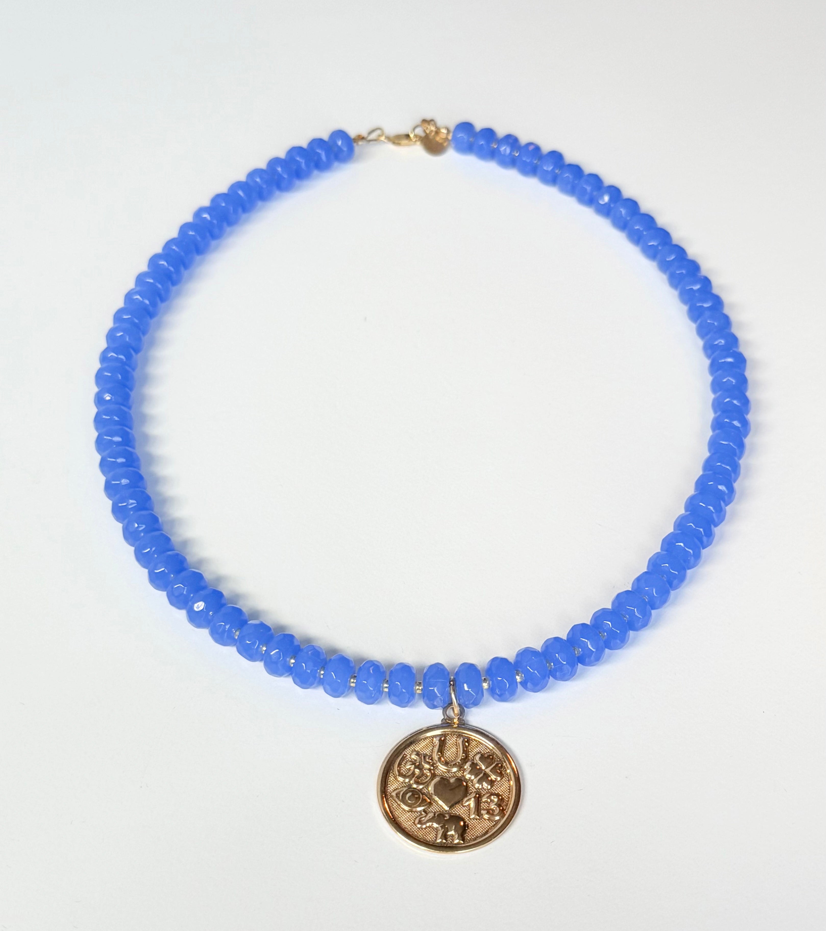 Blue beaded necklace with a gold pendant on a white background