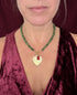 Girl wearing green stone necklace with heart charm and a burgundy background