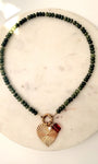 Green stone necklace with heart charm on a marble background