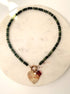 Green stone necklace with heart charm on a marble background